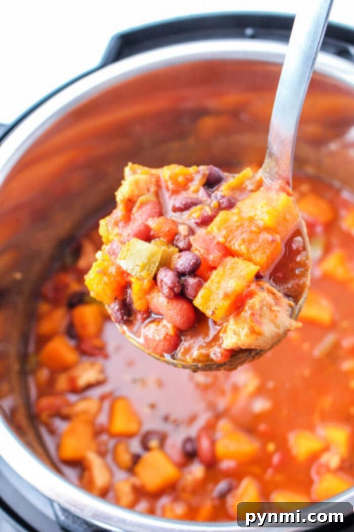A ladle of chunky Sweet Potato Chili Instant Pot stew held over a pot of the same hearty vegetable and bean stew.