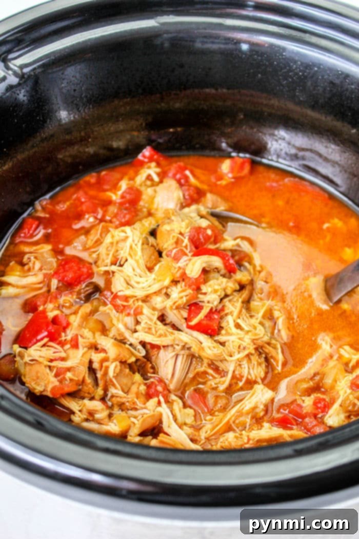Slow Cooker Shredded Chicken Thighs piled high with fresh cilantro and lime wedges.