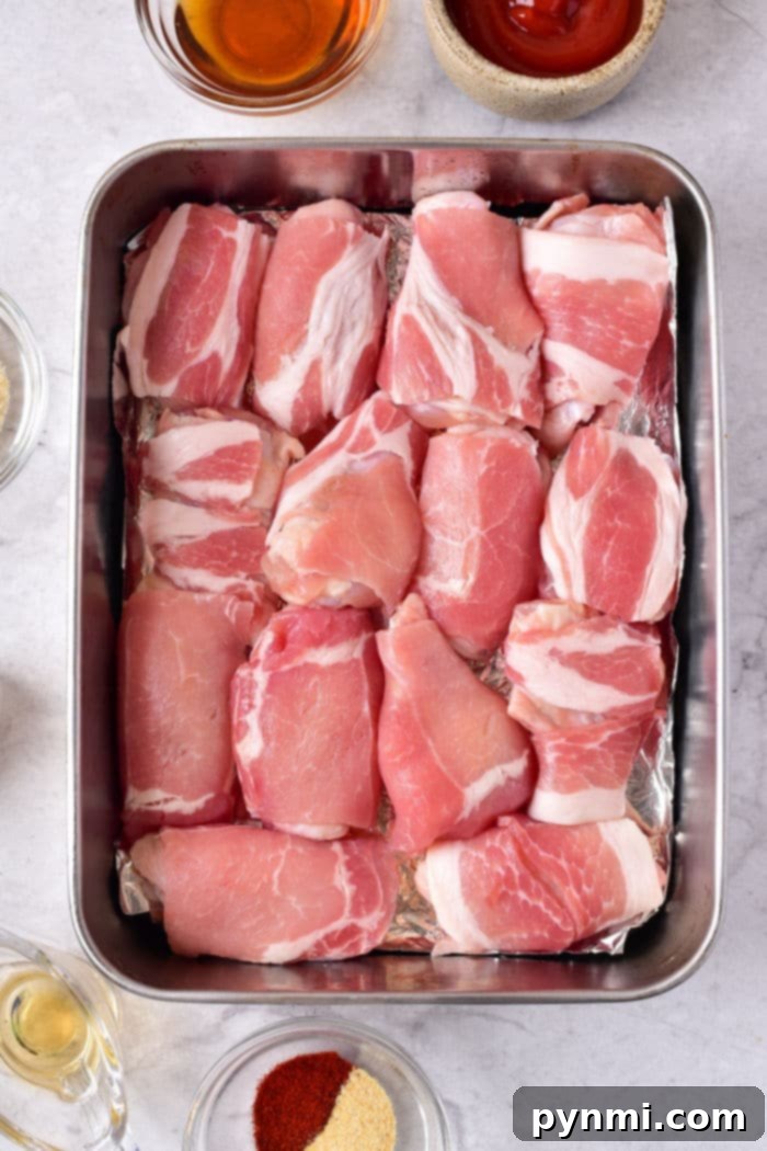 How Long to Bake Chicken Wings at 375°F 4 Perfectly arranged bacon-wrapped chicken wings in a metal baking tray, surrounded by small bowls of spices. A visual guide for how long to cook chicken wings in oven at 375 for crispy perfection.