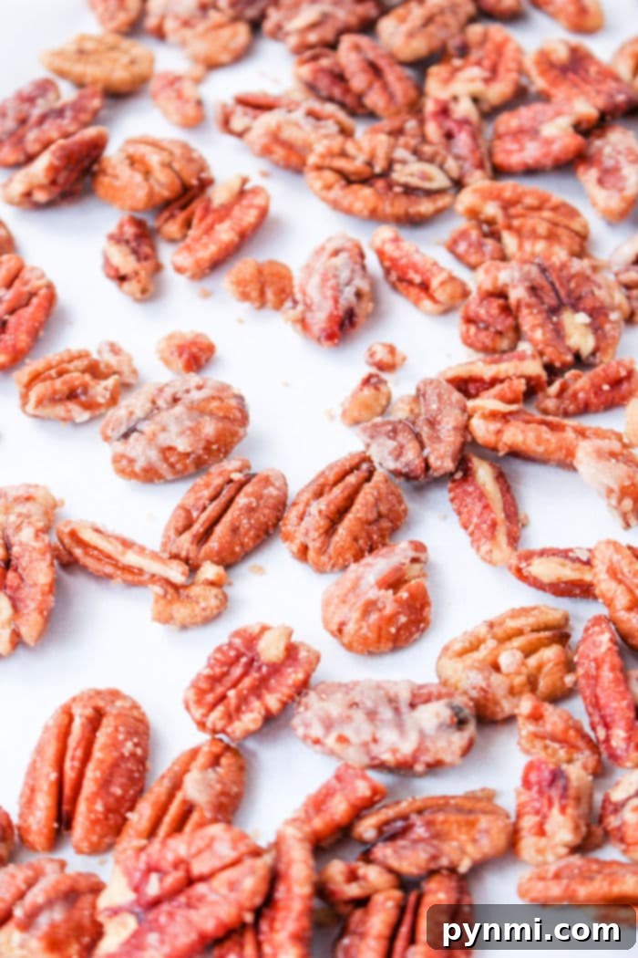 A close-up of assorted candied pecans prepared on the stove, scattered on a white surface.