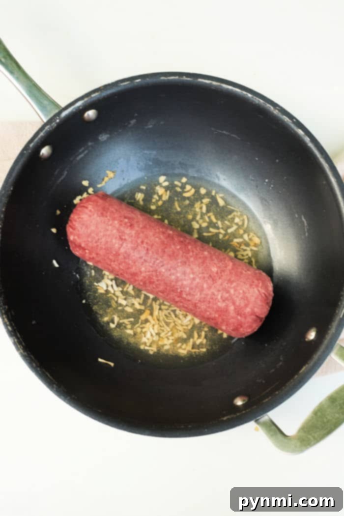 No Thaw Needed: Quick & Delicious Ground Beef Dinners 4 A black frying pan filled with raw frozen ground beef and chopped onions sizzles, reminiscent of a guide on how to cook frozen ground beef.