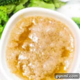 A bowl of Cajun Garlic Butter Sauce next to steamed broccoli florets with a fork.
