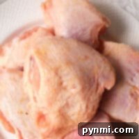 Frozen chicken thighs, perfect for the air fryer, are beautifully piled on a white plate.