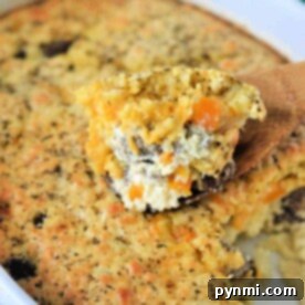 A breakfast casserole with Bisquick, featuring a slice of cheesy vegetable bake, rests invitingly on a wooden spatula.