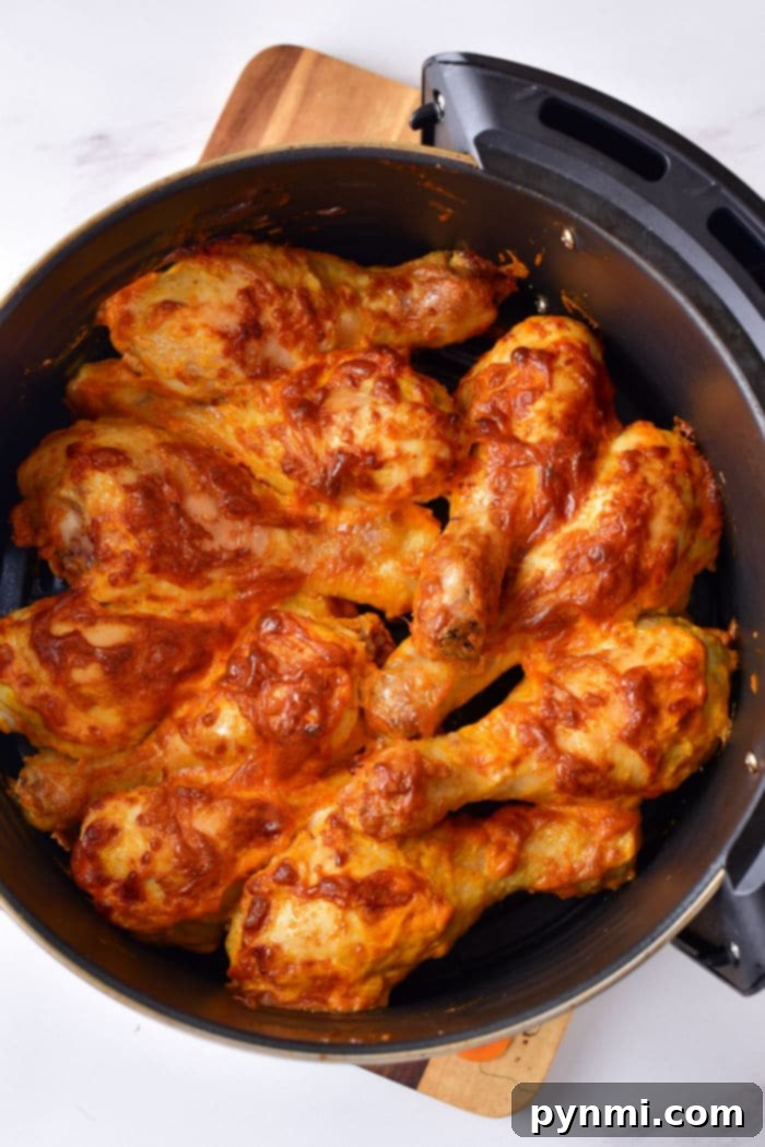 Baked chicken drumsticks coated in sauce rest in a black baking dish on a wooden board, making you wonder how long to boil chicken legs before achieving this savory perfection.