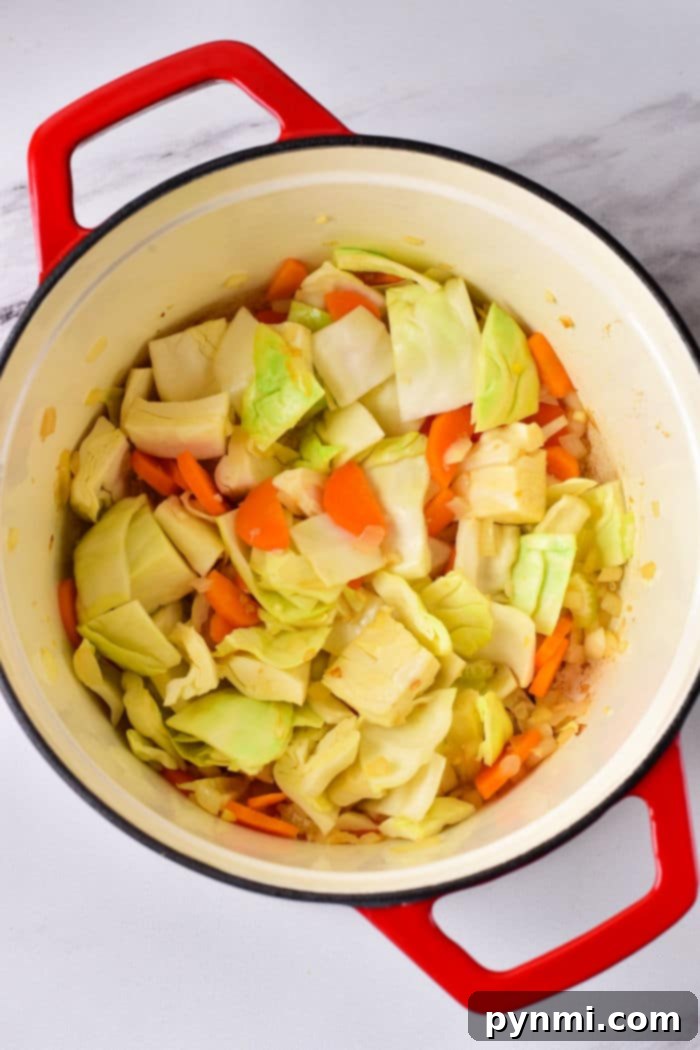 Comforting Cabbage Stew 4 Freshly sliced green cabbage and vibrant orange carrots are prepped and ready for cooking on a light countertop, showcasing the key vegetable ingredients for a healthy stew.
