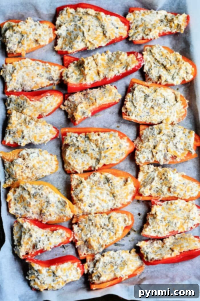 Vibrant red and orange mini sweet peppers, halved and ready for stuffing, arranged on a baking sheet.