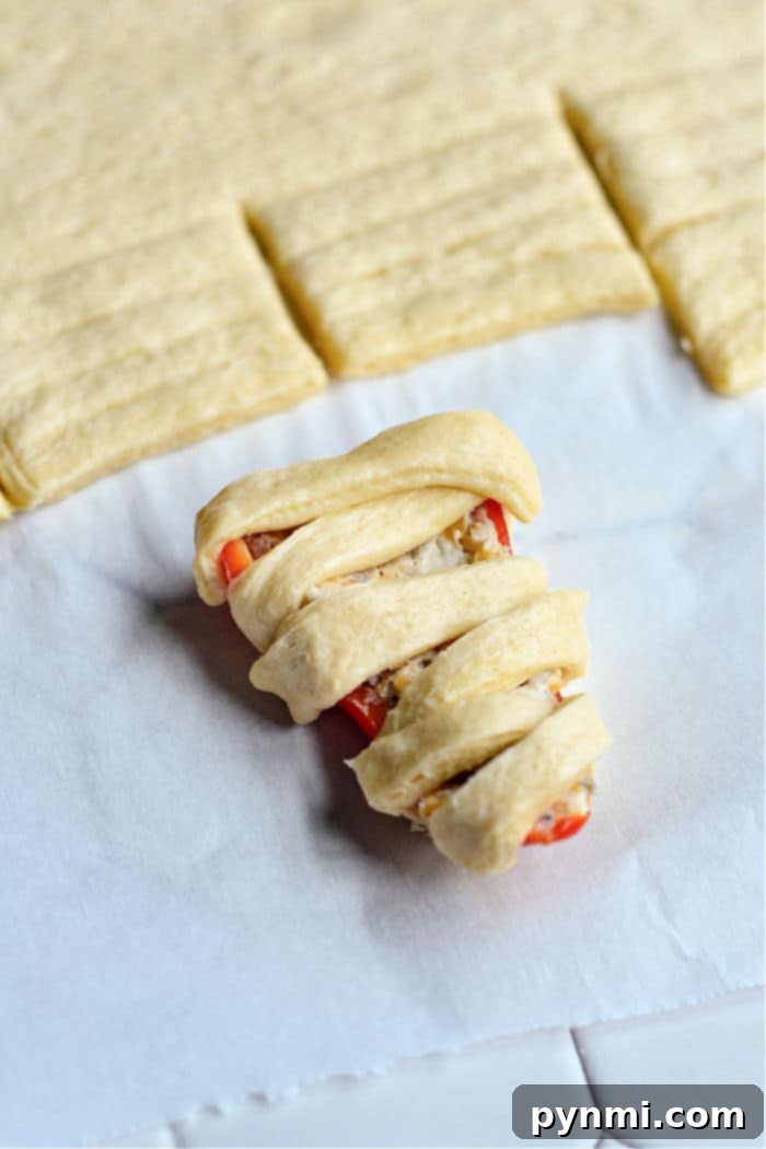 A close-up of baked mini sweet peppers, rich with cream cheese filling, arranged on parchment paper.