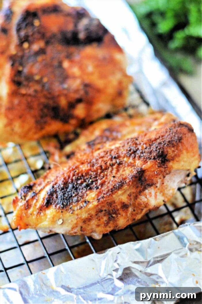 roasted chicken breast with seasoning rests on a wire rack over foil, perfect for even cooking. Curious about oven time? Bake at 350°F for a juicy finish.
