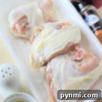 Raw chicken pieces in a white tray with olive oil, spices, salt, pepper, and herbs on the side await their culinary transformation. Perfect for those wondering how long to cook chicken breast in an oven at 350°F for a juicy and flavorful meal.