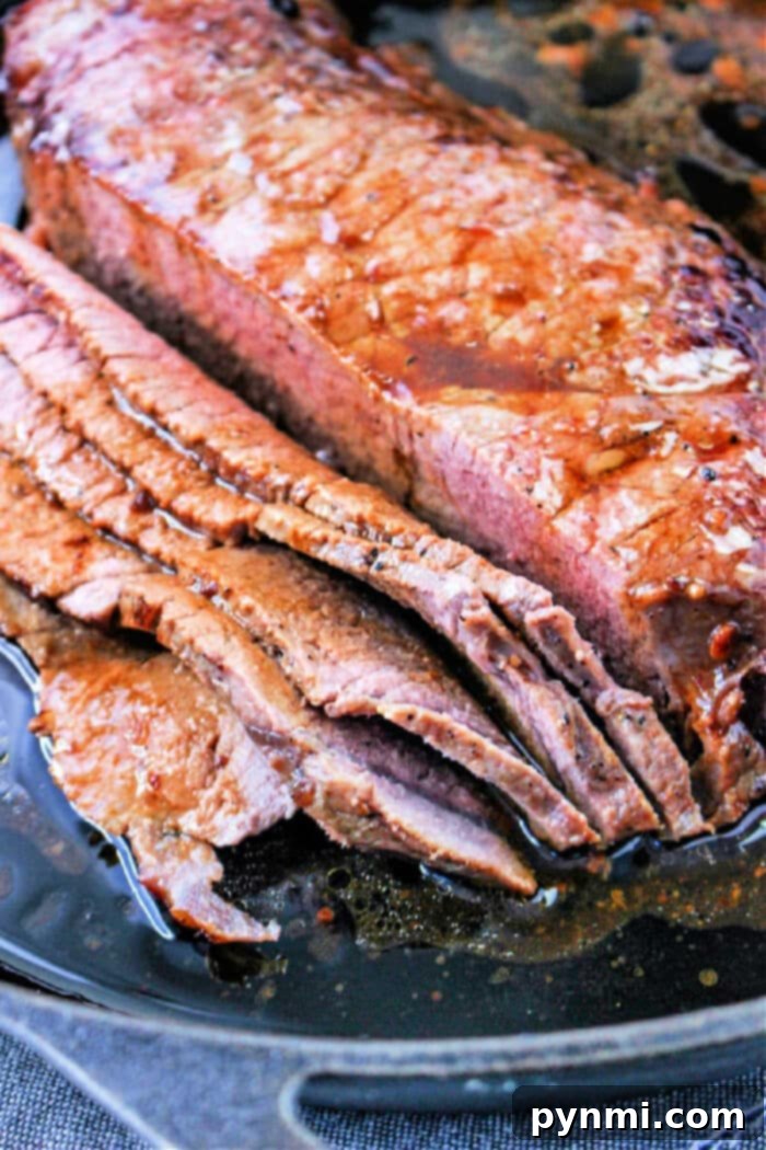 Cast Iron Seared Flank Steak 2 Sliced roasted flank steak nestled in a cast iron pan with flavorful juices, garnished with fresh herbs.