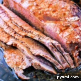 Sliced roasted flank steak nestled in a cast iron pan with flavorful juices.