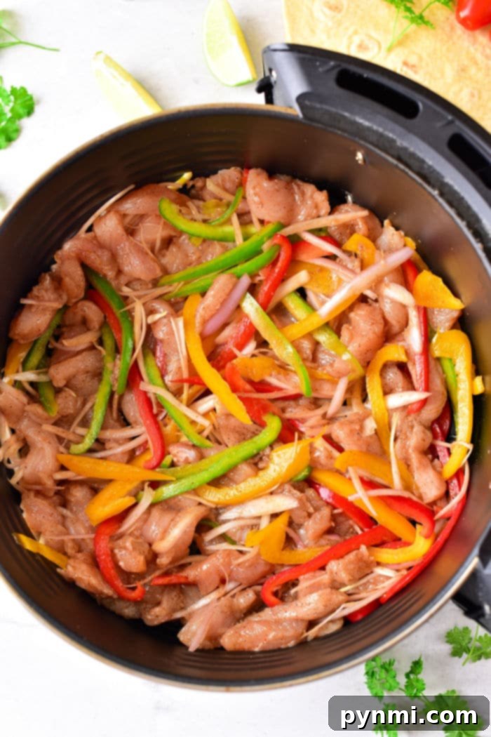 Sizzling Chicken Fajita Wraps 4 Chicken Fajitas Air Fryer - A close-up of chicken and bell peppers cooking in an air fryer basket.