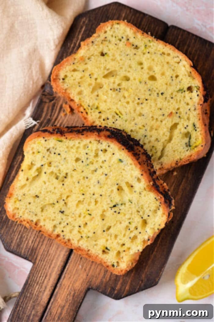 Zesty Lemon Zucchini Loaf 2 Delicious Lemon Zucchini Poppy Seed Bread slices on a cutting board, garnished with lemon zest and poppy seeds.
