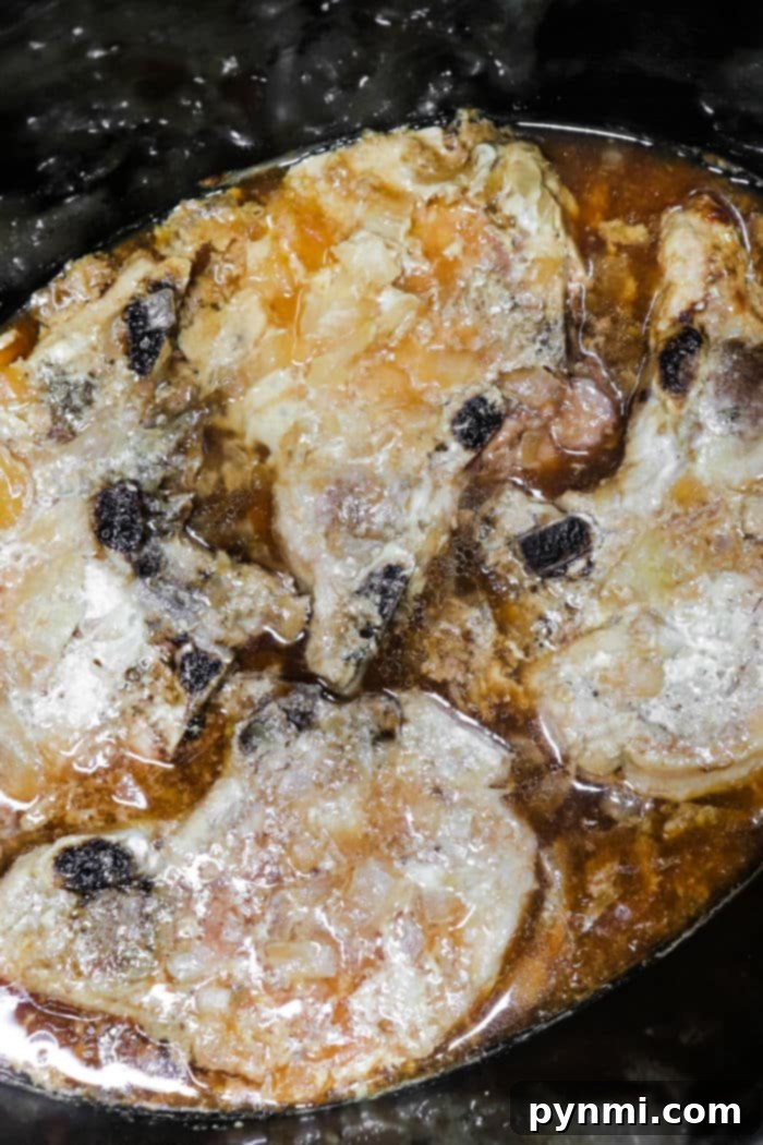 Slow Cooker Frozen Pork Chops simmering in a Rich Gravy