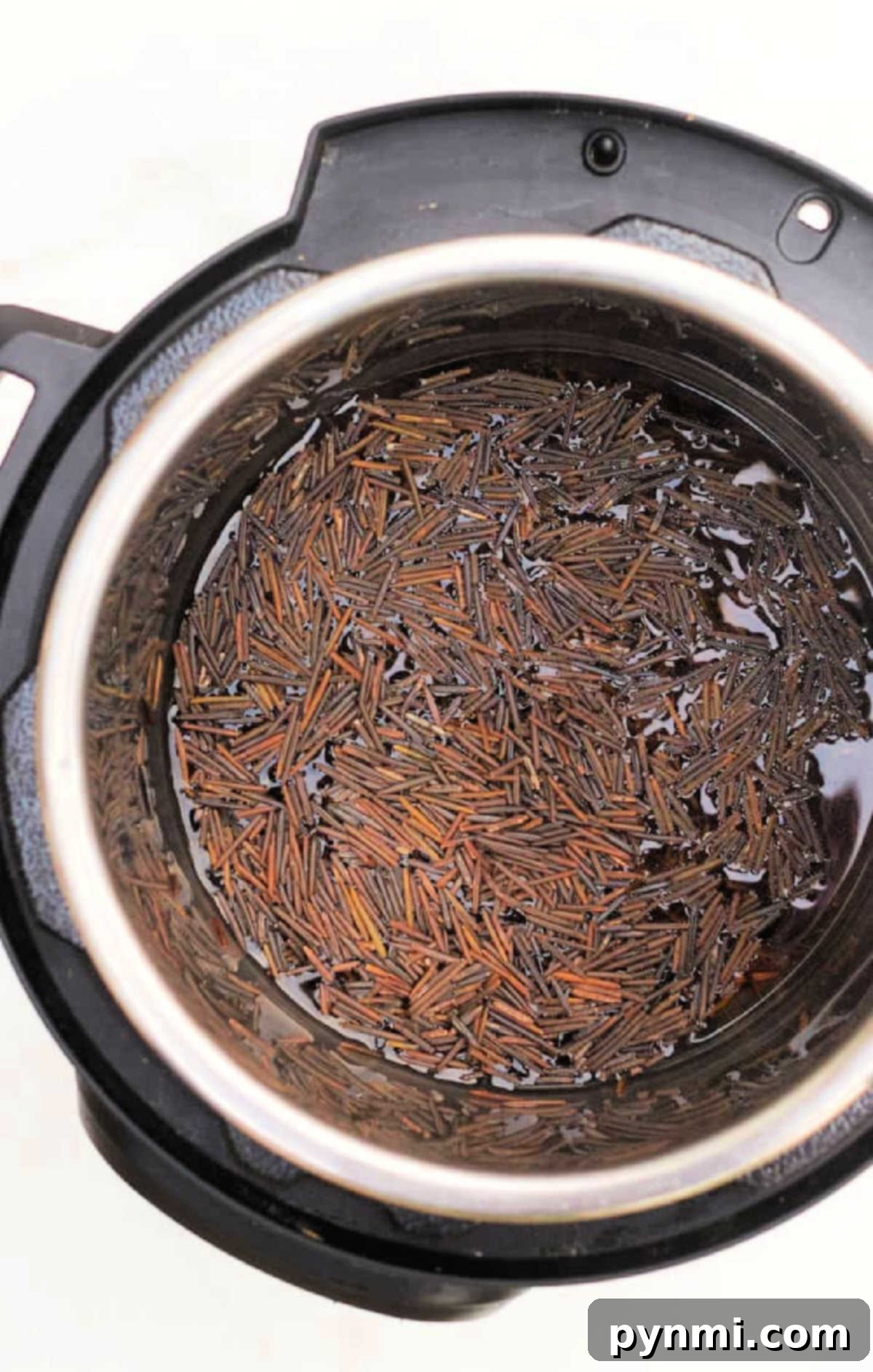 Instant Pot Black Rice Made Easy 4 Uncooked wild and black rice soaking in water inside an Instant Pot, viewed from above, illustrating the preparation stage.