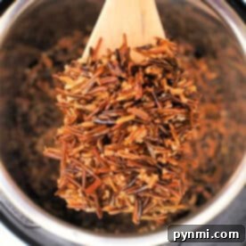 A wooden spoon lifts cooked wild rice from a Black Rice Instant Pot, showing the dark, fluffy grains.