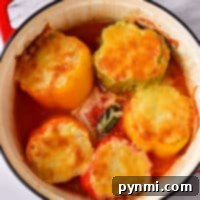 Baked stuffed peppers topped with melted cheese delightfully sit in a red pot on a marble surface, showcasing a perfect balance of flavors. Wondering how long to bake stuffed peppers at 400? The ideal time is about 30 minutes for that deliciously tender result.
