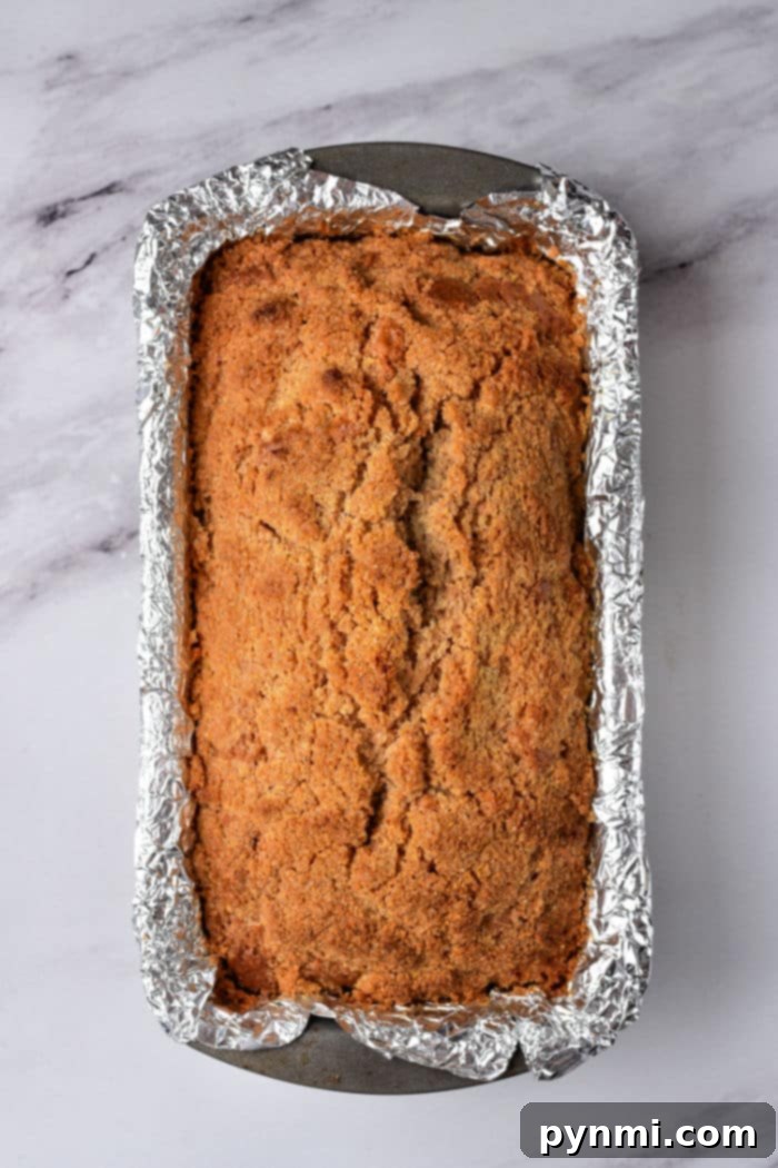 A freshly baked healthy coffee cake loaf rests in a foil-lined pan on a marble surface, perfectly cooled and ready to be enjoyed.