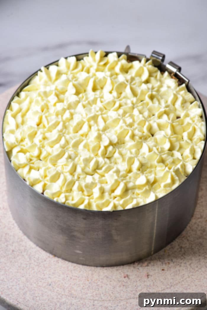 An 8-inch purple cake in a metal mold topped with elegant white frosting swirls.