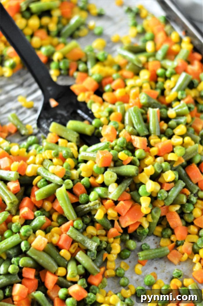 Frozen to Fantastic: Roasting Your Veggies 6 A vibrant collection of oven-roasted frozen vegetables, including tender green beans, sweet corn, peas, and diced carrots, perfectly caramelized and ready to eat. The image poses the question: 'Can You Bake Frozen Vegetables?', which is emphatically answered by the delicious visual.