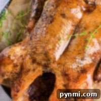 Crispy Roast Duck Perfection 6 A succulent roast duck with golden skin, garnished with fresh thyme, rests enticingly on a parchment-lined plate.