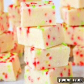 A stack of festive white fudge squares made with cookie mix and condensed milk, adorned with red and green sprinkles on a marble surface.