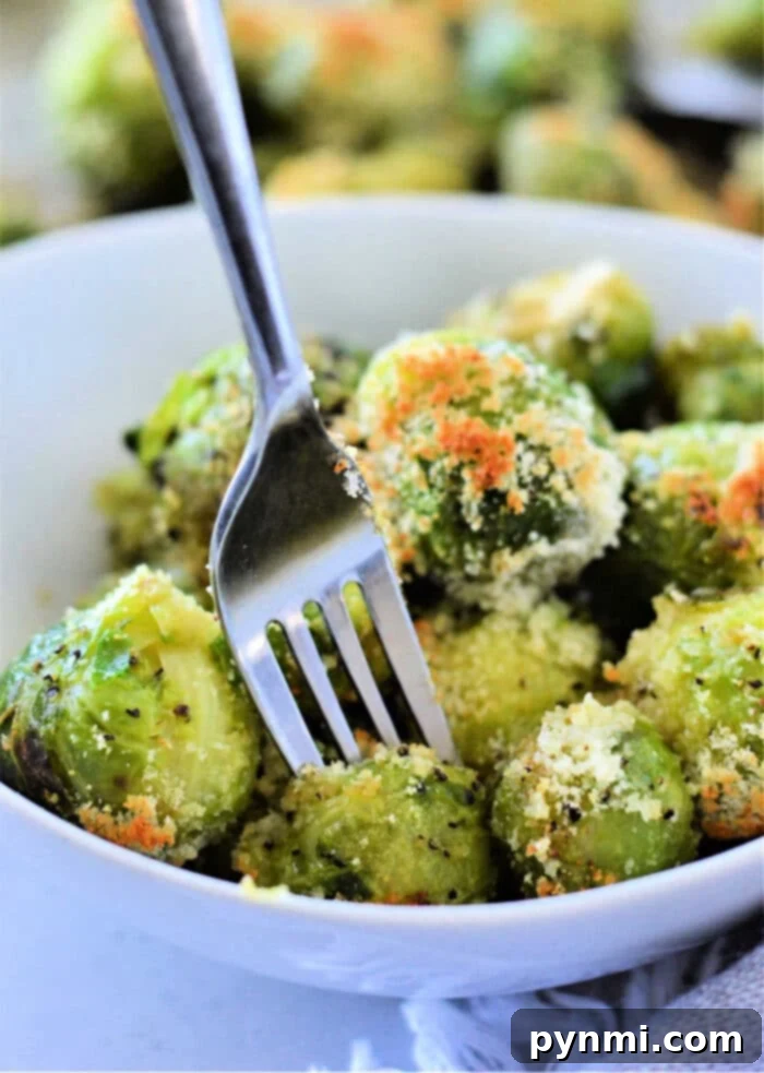 Quick Brussels Bliss 2 A bowl of microwaved Brussels sprouts with Parmesan cheese, how to microwave Brussels sprouts to perfection, all flawlessly pierced by a fork.