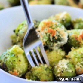 A bowl of microwaved Brussels sprouts with Parmesan cheese, how to microwave Brussels sprouts to perfection, all flawlessly pierced by a fork.