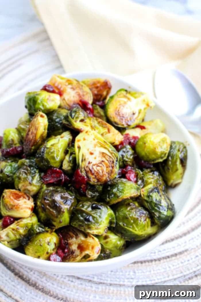 Quick Brussels Bliss 6 A bowl of Brussels sprouts with cranberries sits on the table, accompanied by a spoon, offering a delightful taste. Discover the ease of preparation by learning how to microwave Brussels sprouts for a quick and delicious alternative.