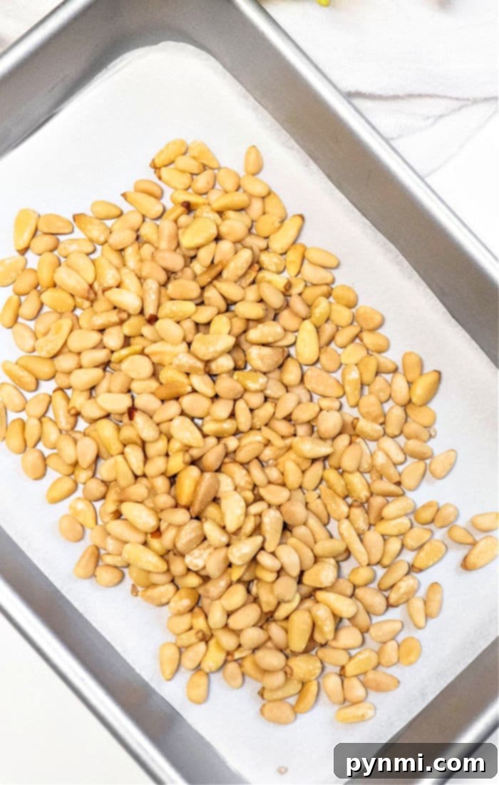 Learn how to roast pine nuts perfectly by starting with them scattered on a parchment-lined baking tray.