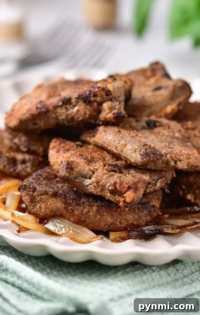 Tender Pan-Fried Beef Liver with Caramelized Onions 6 A plate of fried liver slices stacked on top of caramelized onions, demonstrating how to cook beef liver perfectly for a delectable meal.