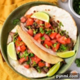 A plate of flavorful cow tongue tacos topped with diced tomatoes, fresh cilantro, and lime wedges sits on a yellow cloth. Nearby, bowls of zesty salsa and creamy guacamole await to complement the vibrant dish.