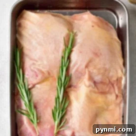 Raw frozen chicken thighs seasoned with rosemary and spices, ready for baking.
