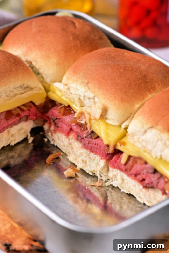 Delicious roast beef sliders on Hawaiian rolls, topped with caramelized onions and melted cheese, ready for a Super Bowl party.