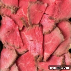 Slices of rare roast beef layered in a metal tray, showing a pink center and browned edges—perfect for anyone wanting to learn How to Cook Melt in the Mouth Roast Beef.