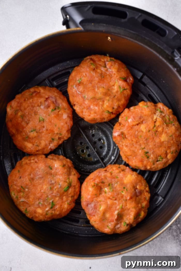 Crispy Air-Fried Salmon Cakes 4 Five raw salmon patties seasoned with herbs sit in an air fryer basket, ready for a modern twist on cooking. These aren't your Old Fashioned Salmon Patties, but they're sure to awaken nostalgic flavors with every bite.