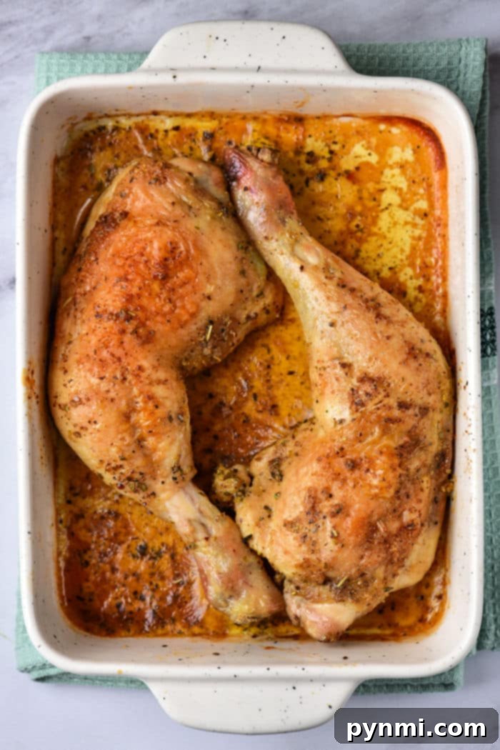 A serving of baked chicken leg quarters on a plate, garnished and ready to eat.