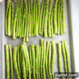 Fresh asparagus spears arranged neatly on a baking tray, perfect for a quick transformation into savory pan-fried asparagus.