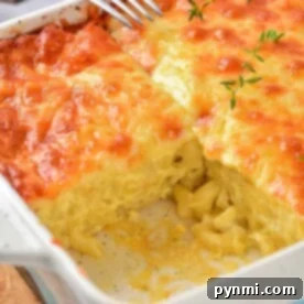A baked mac and cheese with heavy cream casserole boasts a golden, bubbly top and a slice removed, revealing creamy pasta inside.