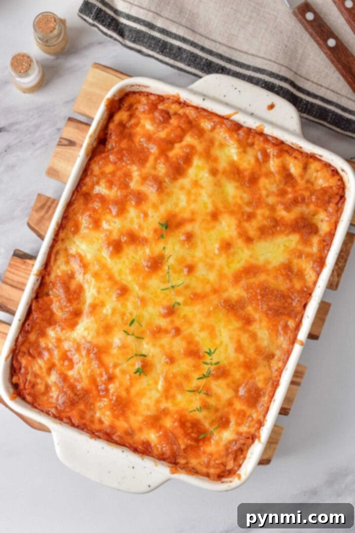 Decadent Heavy Cream Mac and Cheese 7 Golden brown baked mac and cheese richness, nestled in a white casserole dish and crowned with fresh thyme sprigs.