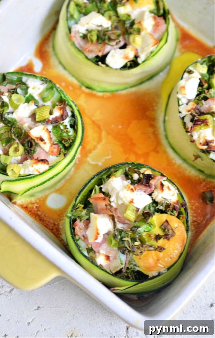 Sunny Zucchini Nests 5 Four colorful zucchini egg cups filled with egg, greens, and cheese, artfully arranged on a white serving plate, highlighting a healthy and delicious breakfast option.
