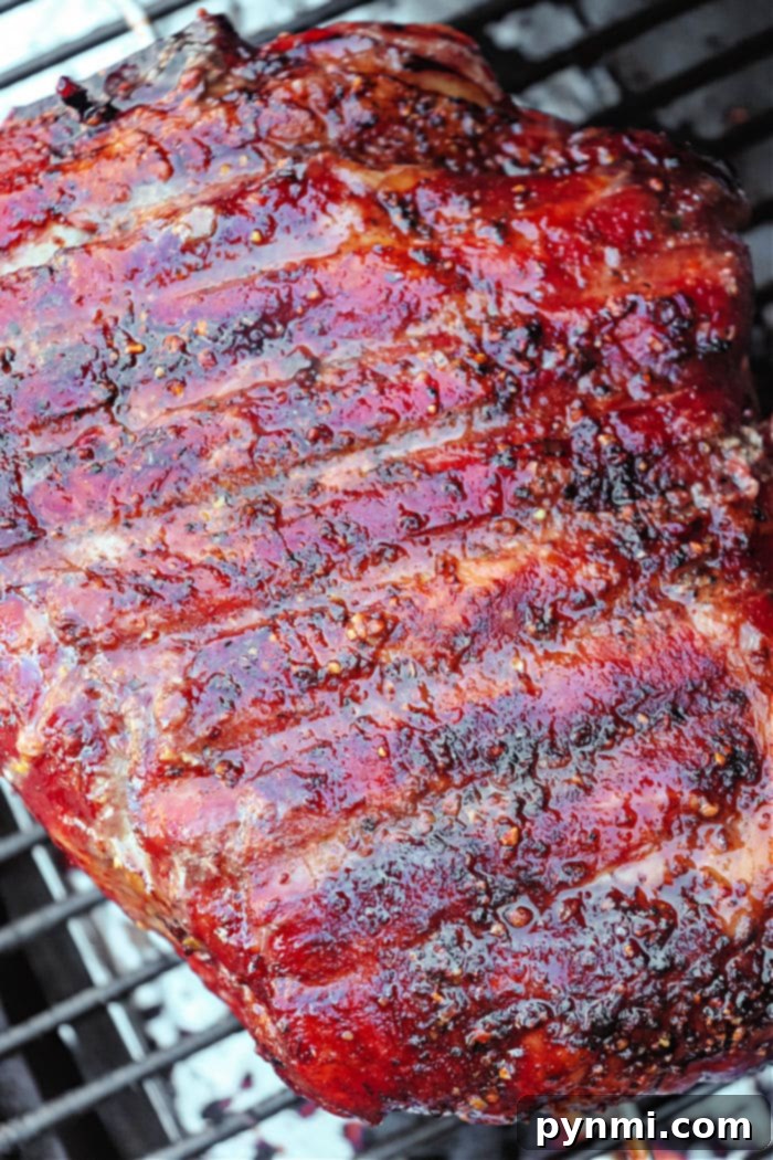 Slow-Smoked Pork Perfection 5 A delicious smoked pork roast sits on a pellet grill, ready to be removed. Its dark, crispy bark and tender appearance promise an excellent meal.