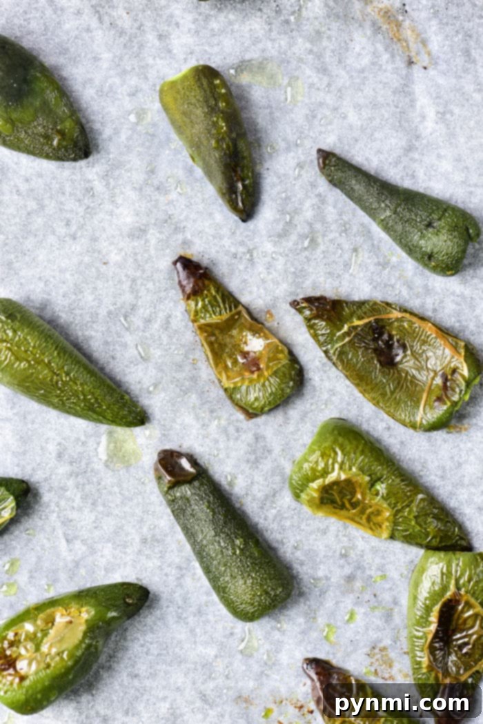 Smoky Oven Roasted Jalapenos 4 Roasted jalapenos on parchment paper.