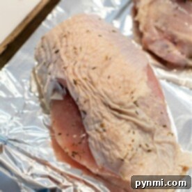 A beautifully roasted turkey breast, adorned with vibrant herbs and boasting a perfectly crisp, golden-brown skin, is featured in a close-up shot. The image captures the succulence and aromatic appeal of the dish, embodying the ideal outcome of "How to Cook a Butterball Turkey Breast."