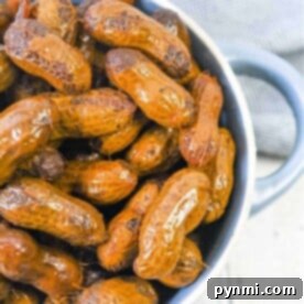 Savory Slow Cooker Peanuts 7 A bowl of Crockpot boiled peanuts sits on a wooden surface, complemented by a gray cloth in the background.