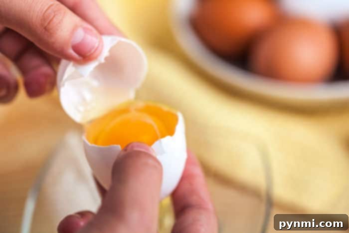 Perfectly Cooked Egg Whites Every Time 4 A close-up image showing the process of separating an egg yolk from its white using the hand method.