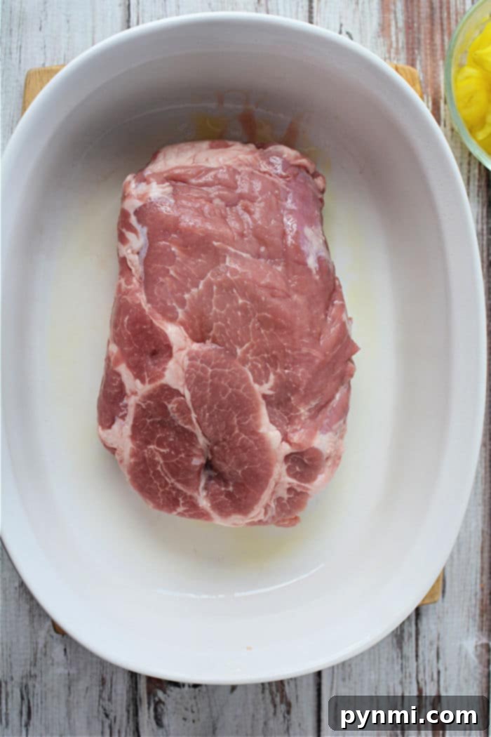 A whole pork roast, seasoned and ready for the oven, resting in a baking dish. The rich marbling promises a tender and flavorful result after cooking.