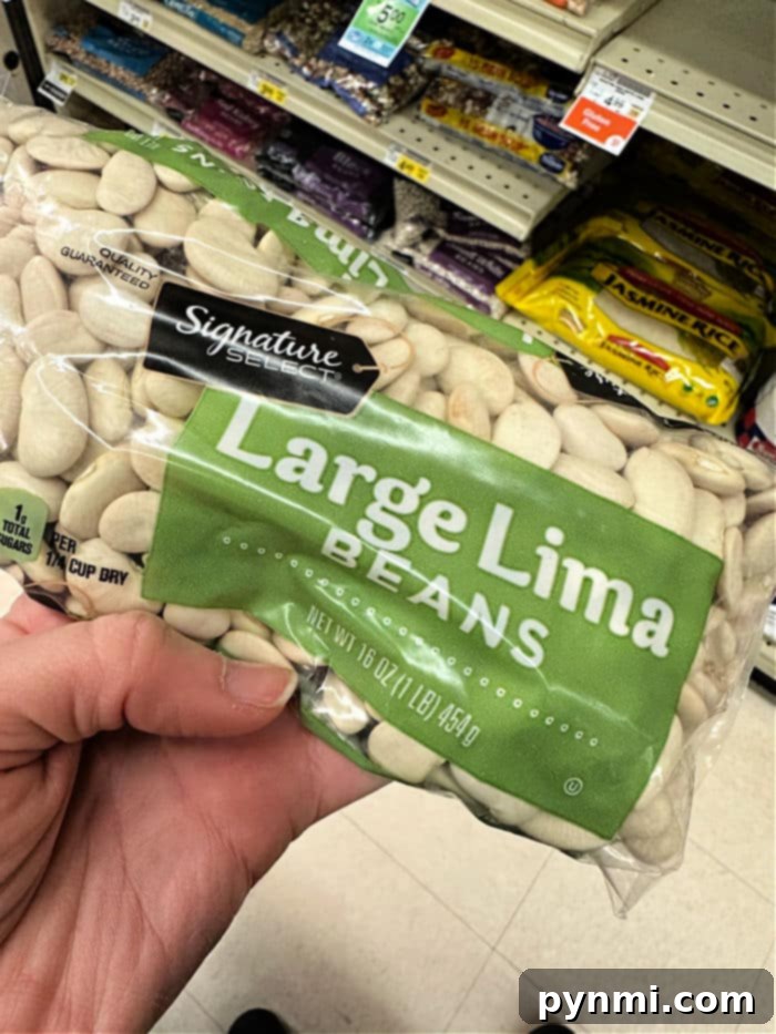 A close-up image of dried lima beans, showcasing their pale, flat, kidney-like shape, ready for soaking and cooking.