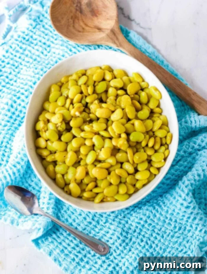 A vibrant bowl of southern-style dried lima beans with visible seasonings, on a wooden surface, highlighting their delicious appeal.